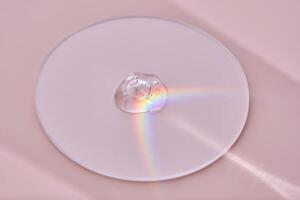 A drop of serum on a round stand on a pink background with beautiful caustics. photo