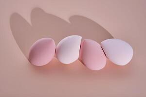 A set of makeup sponges on a pink background. photo