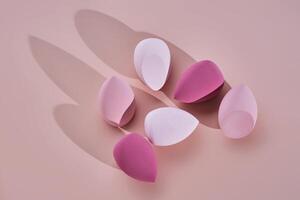 A set of makeup sponges on a pink background. photo