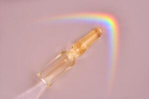 An ampoule with a medical product or cosmetic product on a pink background. photo