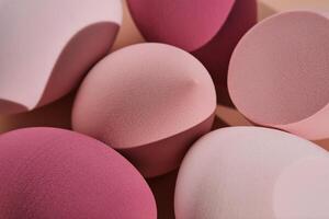 A set of makeup sponges on a pink background. photo