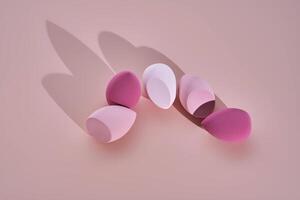 A set of makeup sponges on a pink background. photo