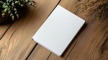 Blank white notebook on wooden table with potted plant photo