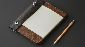 A leather notebook and pencil on a black surface photo