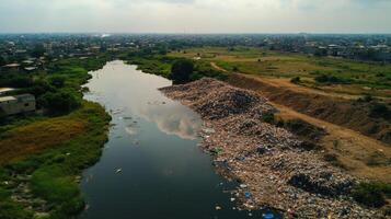 large landfill site filled with piles of plastic waste near river photo