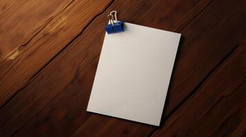 Blank paper with blue clip on wooden background photo