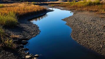 once vibrant river now drained, revealing dry banks and reflections photo