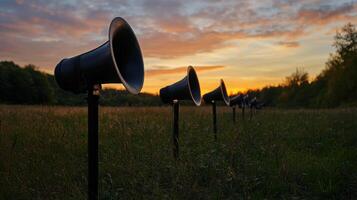 row of loudspeakers in serene countryside at sunset photo