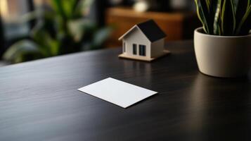 blank business card on table with house model and plant photo