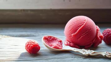 Raspberry ice cream with spoon on wooden table photo