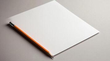 A white notebook with an orange pencil on top photo