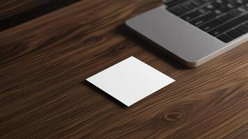 blank business card on wooden desk beside laptop photo