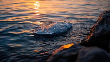 small ice floe glistens in sunset over calm water photo