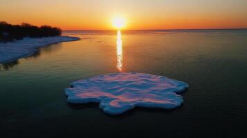 small ice floe surrounded by open water at sunset photo