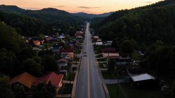 small town with highway surrounded by green hills at sunset photo