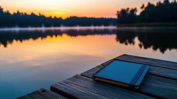 A notebook and a pen on a wooden pier at sunset photo