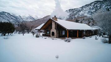 A cabin in the snow with mountains in the background photo