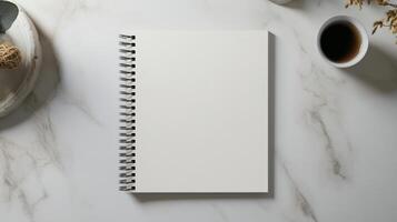 Minimalist spiral notebook on marble surface with coffee photo