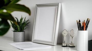 A white desk with a picture frame, a plant and a pair of scissors photo