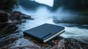 waterproof notebook resting on rock by river photo