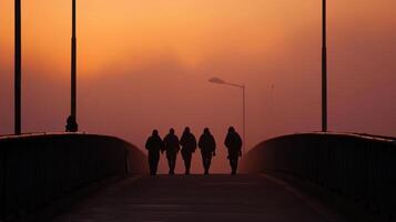 Silhouetted figures walking on bridge at sunset photo