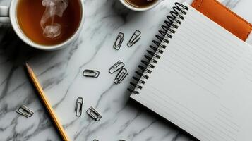 Close up of notebook, pencil, and coffee cups on marble photo
