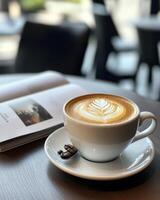 coffee cup with perfect crema on table beside book photo