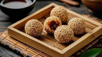 Deep fried sesame balls with sweet filling on wooden tray photo