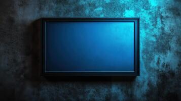 Empty metal picture frame on textured wall with blue light photo