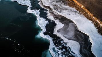 Melting ice forms unique patterns along dark water edge photo