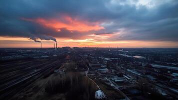 Industrial city skyline at sunset with smoke and clouds photo