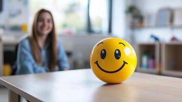 A smiling therapist holds a happy emoji, helping children understand emotions and emotional intelligence in a therapy session. photo