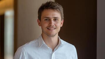 Young Caucasian man in a white shirt smiling in a modern office environment photo