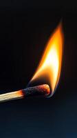 A powerful close-up of a burning matchstick with an intense orange flame, symbolizing ignition, energy, and transformation. photo