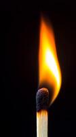 A single matchstick ignited with a strong, dramatic flame against a deep black background, symbolizing energy, ignition, and power. photo