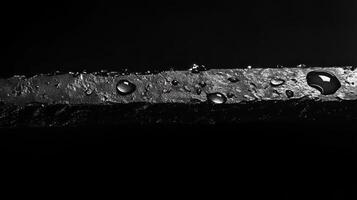 Close-up view of a wet surface with water droplets captured in dramatic lighting showcasing texture and depth photo