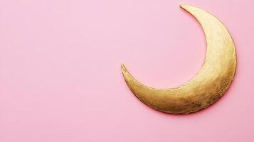 Golden crescent moon ornament rests against a soft pink background, creating a serene and whimsical atmosphere perfect for decor or design inspiration photo