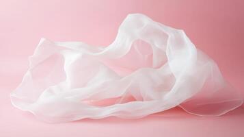 Soft white fabric draped elegantly against a pastel pink background, showcasing delicate textures and lightness in a serene composition photo