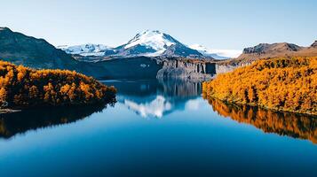 Serene Autumnal Lake with Snow Capped Mountain Reflection Golden Trees photo