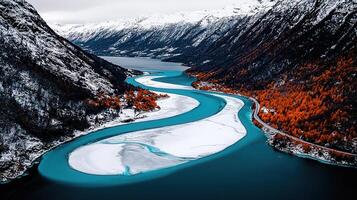 Stunning Aerial View of a Turquoise River Winding Through a Snowy Mountain Landscape with Autumnal Trees photo