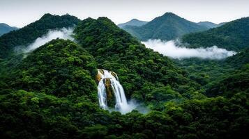 Majestic Waterfall Cascading Through Lush Green Mountains on a Misty Day Serene Nature Scene photo