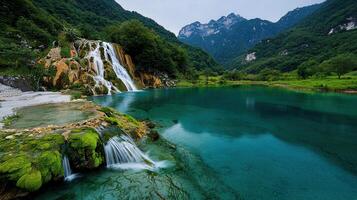 Serene Waterfall cascading into a vibrant turquoise lake nestled within a lush green mountain valley photo