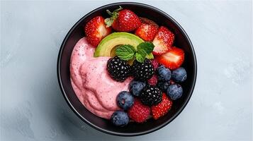 Delicious Pink Smoothie Bowl Topped with Fresh Strawberries Blackberries Blueberries Raspberries and Avocado photo