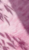 A textured pink surface with shadows, creating an abstract and serene visual. photo