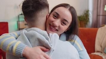 Portrait of woman embracing, hugging man, looking at camera over his shoulder at home room, support video