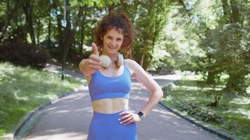 Athletic fit smiling runner girl, happy about marathon achievement showing thumb up like gesture video