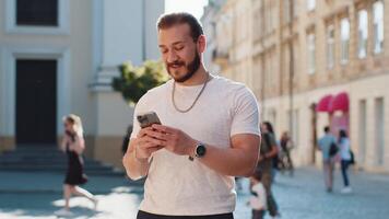Young man use smartphone typing text messages browsing internet finishing work looking at camera video