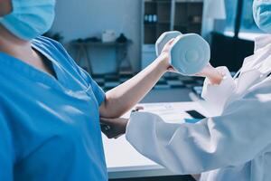 A doctor is holding a dumbbell in front of another person photo