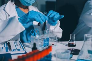 A person in a lab coat and gloves is working on a test tube photo
