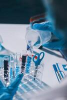 A person in blue gloves is pouring liquid into a test tube photo